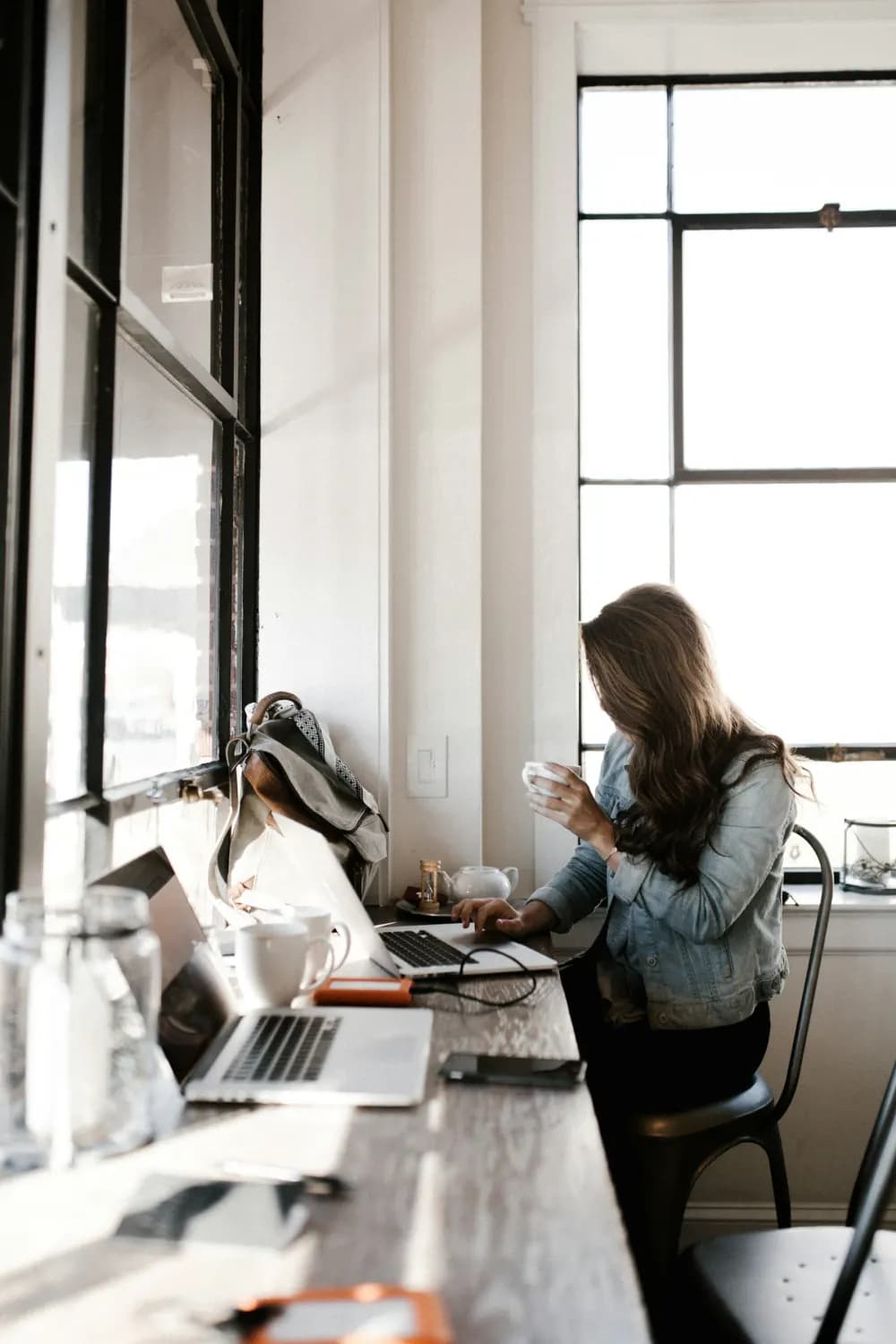 Una freelance al portatile vicino alla finestra, con un caffè